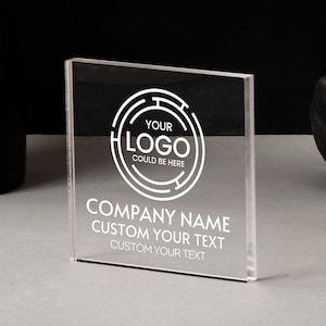 Könnte beinhalten: Ein klarer Acrylschild mit weißem Text und einem kreisförmigen Logo mit der Aufschrift "YOUR LOGO COULD BE HERE". Das Schild zeigt auch "COMPANY NAME" und "CUSTOM YOUR TEXT". Das Schild steht auf einer grauen Oberfläche.