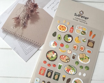 May include: A sheet of colourful food-themed stickers with illustrations of various dishes, including salads, sandwiches, and pasta. The stickers are labelled "Suatelier" and "food trip #5".