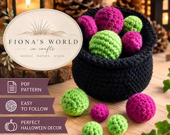 May include: A black crocheted cauldron filled with bright green and magenta crocheted spheres. Additional spheres in the same colors are scattered nearby. The image includes text reading FIONA'S WORLD in crafts, NORDIC NATURE HYGGE, PDF PATTERN, EASY TO FOLLOW, and PERFECT HALLOWEEN DECOR.