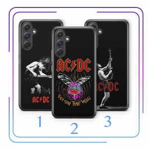 Puede incluir: Tres fundas de teléfono negras con diferentes diseños que presentan a la banda AC/DC. La primera funda tiene una imagen en blanco y negro de una persona tocando la guitarra. La segunda funda tiene una imagen de dibujos animados de una mosca con el texto "AC/DC Fly On The Wall". La tercera funda tiene una imagen en blanco y negro de una persona tocando la guitarra con el texto "AC/DC".