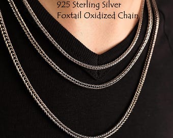 May include: A 925 sterling silver foxtail oxidized chain necklace. The metal has a dark, weathered finish with a complex, woven link pattern. The chain is displayed in multiple layers against a black fabric background with the text 925 Sterling Silver Foxtail Oxidized Chain visible.