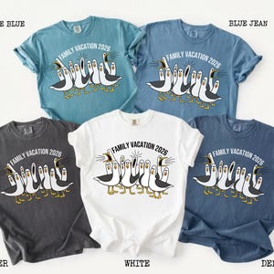 May include: Five short-sleeve t-shirts in ice blue, blue jean, pepper, white, and denim colors. Each shirt features a graphic of multiple seagulls with open beaks and the text "FAMILY VACATION 2026" printed in an arc above the birds.