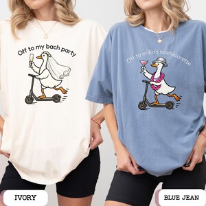 May include: Ivory and blue jean t-shirts with a cartoon goose riding a scooter, holding a drink, and wearing a veil or lei. Text on the shirts reads "Off to my bach party" and "Off to erika's bachelorette".