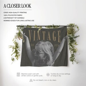 May include: A dark gray rectangular polyester wall tapestry featuring a black and white photograph of a child wearing round sunglasses with arms raised. The text VINTAGE EST. 1976 is printed in a tan serif font across the top of the image.