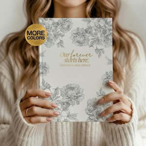 Op de afbeelding: Een crèmekleurig notitieboek met een bloemenontwerp en de tekst "Our forever starts here." De omslag heeft een gedetailleerde zwart-wit pioenroos illustratie. De namen "Samantha and Joshua" staan eronder gedrukt.