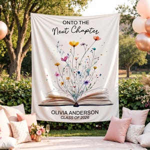 Peut inclure: Bannière de remise de diplôme blanche avec le texte « ONTO THE Next Chapter » et une illustration florale à l'aquarelle émergeant d'un livre ouvert. La bannière comprend le nom « OLIVIA ANDERSON » et « CLASS OF 2026 ».