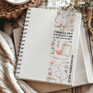 K&ouml;nnte beinhalten: Ein Spiralnotizbuch mit wei&szlig;em Einband mit einem Aquarelldesign von medizinischen Ger&auml;ten. Der Text "THINGS MY PATIENTS SAID so I'll never forget" ist auf dem Einband aufgedruckt, zusammen mit dem Namen "OLIVIA ANDERSON RN".