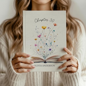 Puede incluir: Un libro de tapa dura con el título "Chapter 30" y el nombre "Olivia Anderson" en la portada. La portada presenta una ilustración de acuarela de flores silvestres coloridas. El libro está abierto, revelando las páginas.
