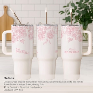 May include: White insulated tumblers with pink floral designs and text. One says "IN MY ENGAGED Era", another says "MRS", and the third says "Future MRS. ANDERSON". Each tumbler has a handle and a straw.