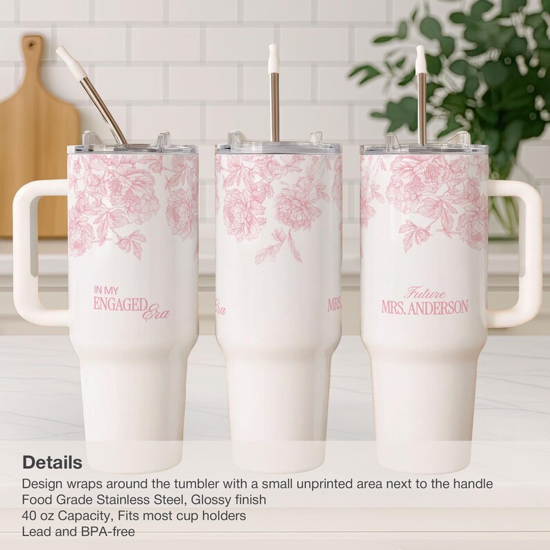 May include: White insulated tumblers with pink floral designs and text. One says "IN MY ENGAGED Era", another says "MRS", and the third says "Future MRS. ANDERSON". Each tumbler has a handle and a straw.