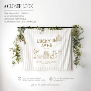 Pode incluir: Uma tape&ccedil;aria listrada em branco e bege com o texto "Lucky in Love" e "Olivia's bachelorette Las Vegas, NV". A tape&ccedil;aria tem ilustra&ccedil;&otilde;es de coquet&eacute;is, dados, cartas de baralho e uma bola de discoteca. O texto "Est. 2026" tamb&eacute;m est&aacute; inclu&iacute;do.
