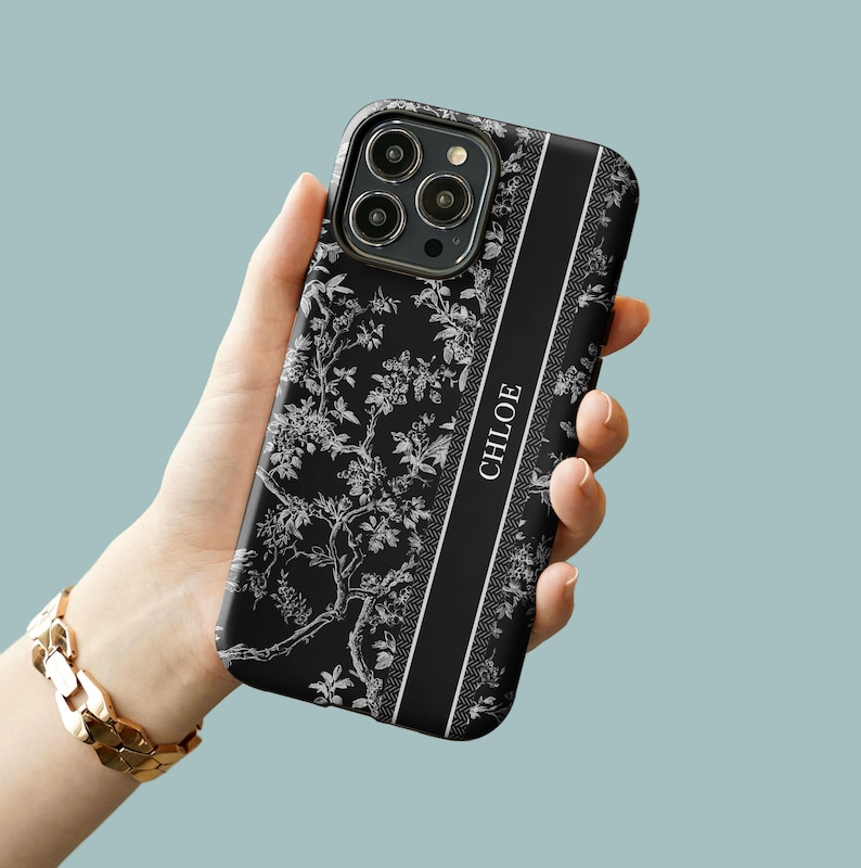 May include: Black phone case with a white floral pattern and a black stripe down the side that says "CHLOE".