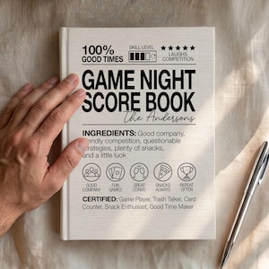 May include: A white hardcover score book with black text reading Game Night Score Book, The Andersons, and a list of ingredients including good company, fun games, and snacks. The cover features icons for people, cards, glasses, pizza, and a trophy.