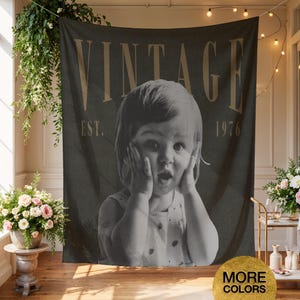 May include: A rectangular wall tapestry featuring a black and white photograph of a young child with hands on their cheeks. The word VINTAGE is printed in large tan letters at the top, with EST. 1976 printed in smaller tan letters below it.