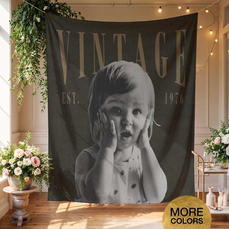 May include: A rectangular wall tapestry featuring a black and white photograph of a young child with hands on their cheeks. The word VINTAGE is printed in large tan letters at the top, with EST. 1976 printed in smaller tan letters below it.