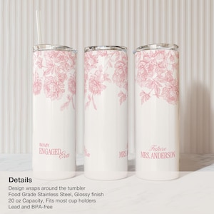 May include: White stainless steel tumblers with pink floral designs. One tumbler reads "In My Engaged Era," another "Mrs," and the third "Future Mrs. Anderson." Each tumbler has a silver lid and a clear straw.