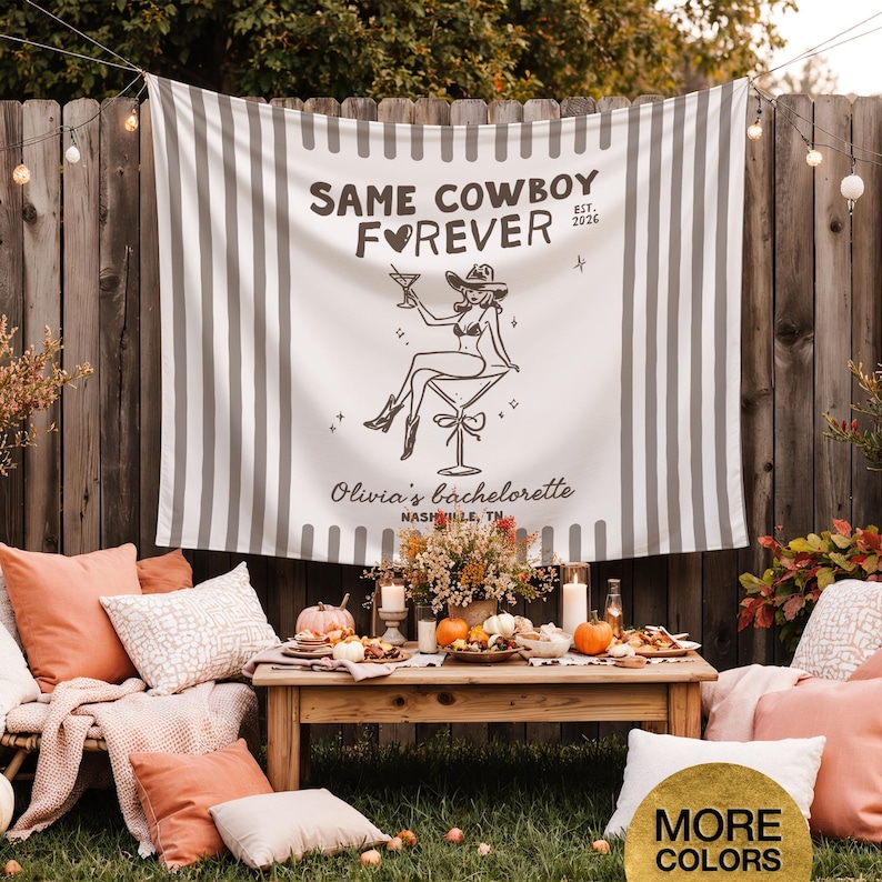 以下が含まれることがあります： 「SAME COWBOY FOREVER」の文字とカウボーイハットをかぶった女性のグラフィックが描かれた、白とグレーのストライプのバナー。「Olivia's bachelorette, Nashville, TN」と書かれています。枕、カボチャ、木製のテーブルが写っています。