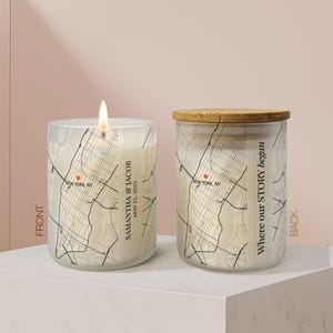 May include: Two glass candles with a map of New York, NY, featuring a red heart icon. The front candle is lit and displays the text "SAMANTHA & JACOB MAY 21, 2025". The back candle has a bamboo lid and the text "Where our STORY began".