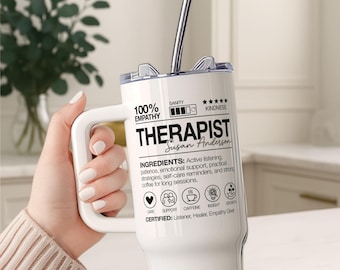May include: White insulated tumbler with a handle and a silver straw. The tumbler features the word "THERAPIST" in large black letters, along with the name "Susan Anderson." Text includes "100% EMPATHY" and "INGREDIENTS: Active listening..."