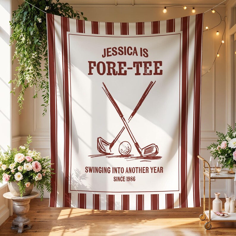 May include: A white golf-themed banner with burgundy stripes and text. The banner reads "JESSICA IS FORE-TEE" with crossed golf clubs and a golf ball. Additional text says "SWINGING INTO ANOTHER YEAR SINCE 1986".