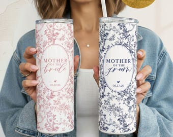 May include: Two stainless steel tumblers with floral patterns. One is pink with "Mother of the Bride" text, the other is blue with "Mother of the Groom". Both have a date and a straw.