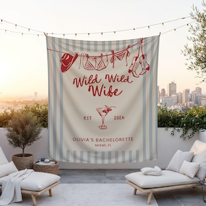 Puede incluir: Un tapiz a rayas beige y azul con ilustraciones rojas de un sombrero de vaquero, lencer&iacute;a y botas colgadas de un tendedero. El texto dice "Wild Wild Wife" y "Olivia's Bachelorette Miami, FL".