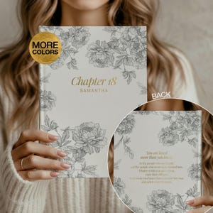 May include: A hardcover journal with a light gray cover featuring a dark gray floral line art pattern. The front displays the gold text "Chapter 18" and "SAMANTHA". The back cover features the gold text "You are loved more than you know."