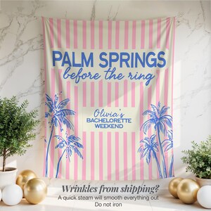 May include: A pink and cream striped banner with the text "PALM SPRINGS before the ring" in blue. The banner also features palm tree illustrations and the text "Olivia's BACHELORETTE WEEKEND".
