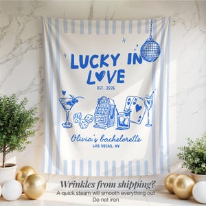 Pode incluir: Fundo branco e azul para despedida de solteira com o texto "LUCKY IN LOVE" e "EST. 2026". O design inclui ilustra&ccedil;&otilde;es de um martini, dados, uma m&aacute;quina ca&ccedil;a-n&iacute;queis, cartas de baralho e uma bola de discoteca. O texto "Olivia's bachelorette LAS VEGAS, NV" tamb&eacute;m est&aacute; inclu&iacute;do.