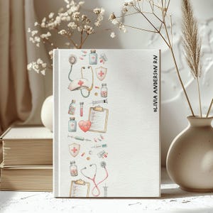 May include: A white notebook with a medical-themed border featuring a stethoscope, pills, and a nurse's hat. The text "OLIVIA ANDERSON RN" is printed vertically on the right side. The notebook is decorated with watercolour illustrations of medical supplies.