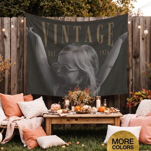 May include: A rectangular wall tapestry featuring a black and white photograph of a child with arms raised, wearing sunglasses. The text VINTAGE is printed in large gold letters at the top, with EST. 1976 centered below the word in smaller gold font.