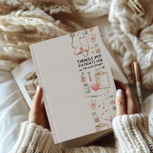 K&ouml;nnte beinhalten: Ein cremefarbenes Notizbuch mit dem Text "THINGS MY PATIENTS SAID so I'll never forget." Das Notizbuch zeigt medizinische Illustrationen, darunter ein Stethoskop, ein Herz und Medikamentenflaschen. Das Notizbuch wird von einer Person gehalten, die einen cremefarbenen Pullover tr&auml;gt.