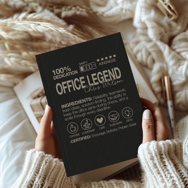 May include: A black notebook with the text "OFFICE LEGEND" and the name "Chris Wilson" in a handwritten font. The notebook also includes the words "100% DEDICATION", "SANITY", and "KINDNESS". The notebook is held open.