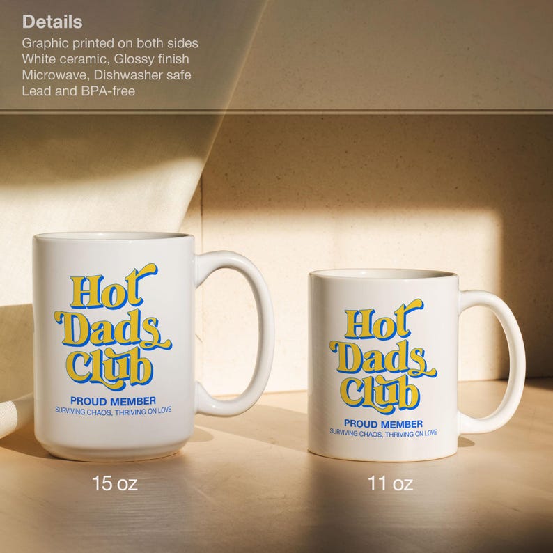 May include: Two white ceramic mugs with the text "Hot Dads Club" in yellow and blue. The mugs are labeled 15 oz and 11 oz. The mugs have a glossy finish and are microwave and dishwasher safe.