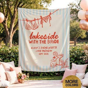 May include: A cream-colored banner with light blue vertical stripes and red text that reads "lakeside with the bride." The banner also features illustrations of bikinis, cocktails, and the text "Olivia's Bachelorette, Lake Michigan, Sept 2026."
