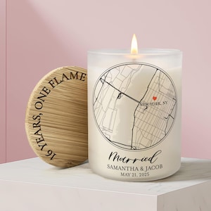 May include: A frosted glass candle with a lit wick, featuring a circular black map graphic of New York, NY with a red heart, the text Married, Samantha & Jacob, May 21, 2025, and a bamboo lid engraved with the text 16 YEARS, ONE FLAME.