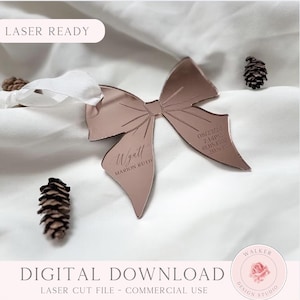 May include: A rose gold bow-shaped laser-cut decoration with the name "Wyatt" and birth details. The bow has a ribbon and is surrounded by pine cones. Text on the bow includes the date, time, weight, and length. The words "Laser Ready" and "Digital Download" are also visible.