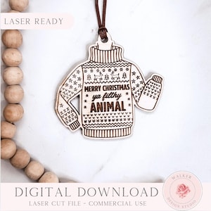 May include: Wooden Christmas sweater ornament with the text "MERRY CHRISTMAS ya filthy ANIMAL". The laser-cut design features a sweater with snowflakes and reindeer. Includes a brown string for hanging.