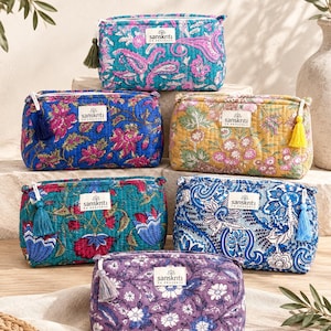 Peut inclure: Une collection de six trousses rectangulaires matelassées avec divers motifs floraux et cachemire dans des tons de bleu, rose, jaune et violet. Chaque trousse possède une fermeture éclair avec un pompon et une étiquette blanche sanskriti en provence.