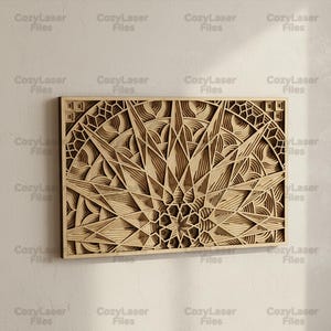 Puede incluir: Una pieza de arte mural de madera en capas con un diseño geométrico. La obra de arte presenta un patrón central de estrella con líneas radiales y detalles intrincados. La pieza está enmarcada en forma rectangular y tiene el texto "CozyLaser Files".