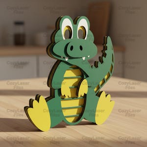 May include: A layered wooden alligator figurine in shades of green, yellow, and white. The alligator has a friendly expression, with large eyes and a toothy grin. The figurine is sitting with its legs extended and tail curved.