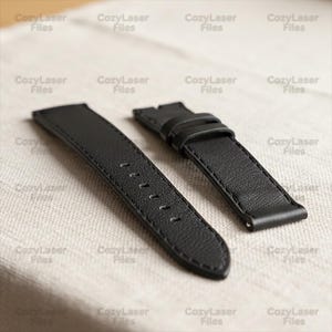May include: Two black leather watch straps. One strap has several holes for adjustment, and the other has a buckle. The straps are lying on a light-colored, textured surface. The text "CozyLaser Files" is repeated across the image.