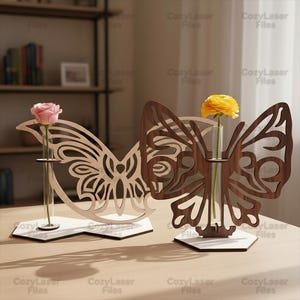 May include: Two butterfly-shaped wooden vases, one light and one dark, each holding a single flower in a glass tube. The vases are on white hexagonal bases. The text "CozyLaser Files" is visible.