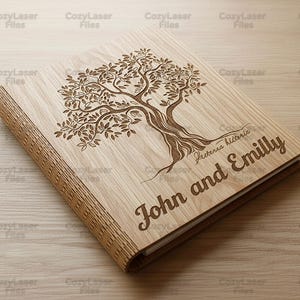 May include: A wooden photo album with a laser-engraved tree design on the cover. The album is light brown with the names "John and Emilly" and the text "Fecterna hitteric" engraved on the cover.