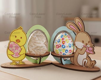May include: Wooden Easter decorations featuring a yellow chick holding a floral egg, and a brown bunny with a pink treat. Two egg-shaped holders display decorative eggs. The decorations are on a wooden base.