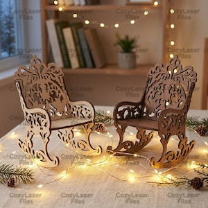 May include: Two miniature rocking chairs crafted from laser-cut wood. One chair features a light natural wood finish, while the other has a darker brown wood tone. Both chairs display intricate, ornate scrollwork patterns on the backrests and sides.
