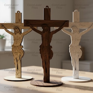 May include: Three wooden crucifix sculptures in shades of brown and beige. Each depicts Jesus on the cross, mounted on a circular base. The text "CozyLaser Files" is visible. The sculptures are suitable for display.
