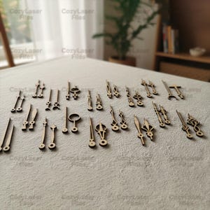 May include: A collection of various wooden clock hands and decorative elements, laser-cut from light-colored wood. The pieces are arranged on a neutral-toned surface, showcasing a variety of shapes and sizes, ideal for DIY clock projects.