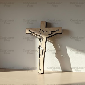 Può includere: Un crocifisso in legno di colore chiaro caratterizzato dalla sagoma tagliata al laser di una figura con le braccia tese. Il design è definito da linee pulite e nette e da una finitura liscia, creando un forte contrasto tra il legno chiaro e lo spazio negativo scuro della figura ritagliata.