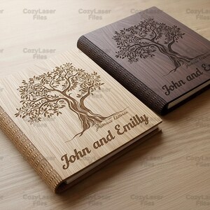 May include: Two wooden books with engraved tree designs. One book is light-colored, the other is dark. Both books have the names "John and Emilly" engraved on the cover. The books are on a light-colored wooden surface.